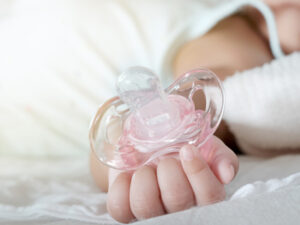Baby hält im Schlaf einen Schnuller in der Hand