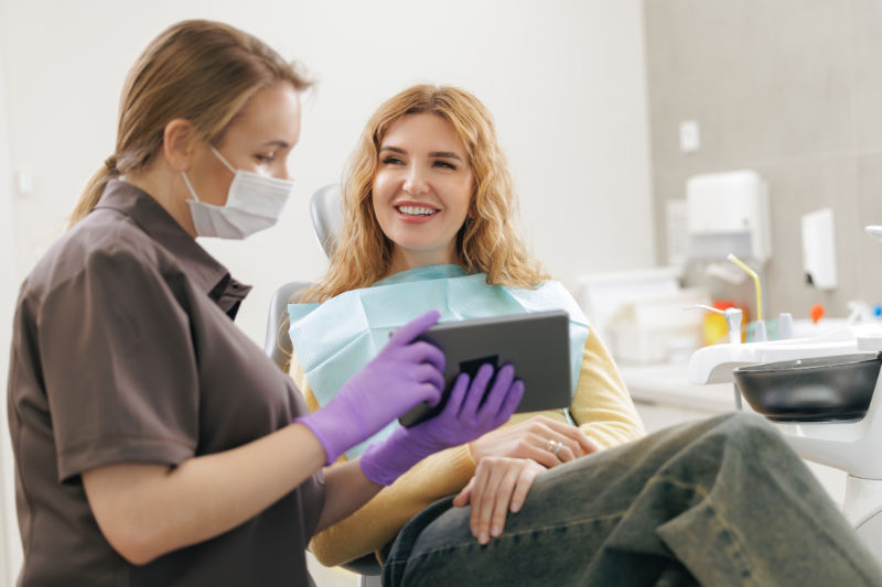 Patientin in der Zahnarztpraxis wird Systemische Zahnmedizin erklärt