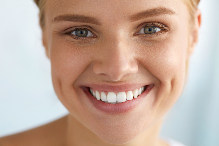 Beautiful Woman With Beauty Face, Healthy White Teeth Smiling Nahaufnahme einer Patientin mit gesundem, strahlendem Lächeln, die direkt in die Kamera schaut.